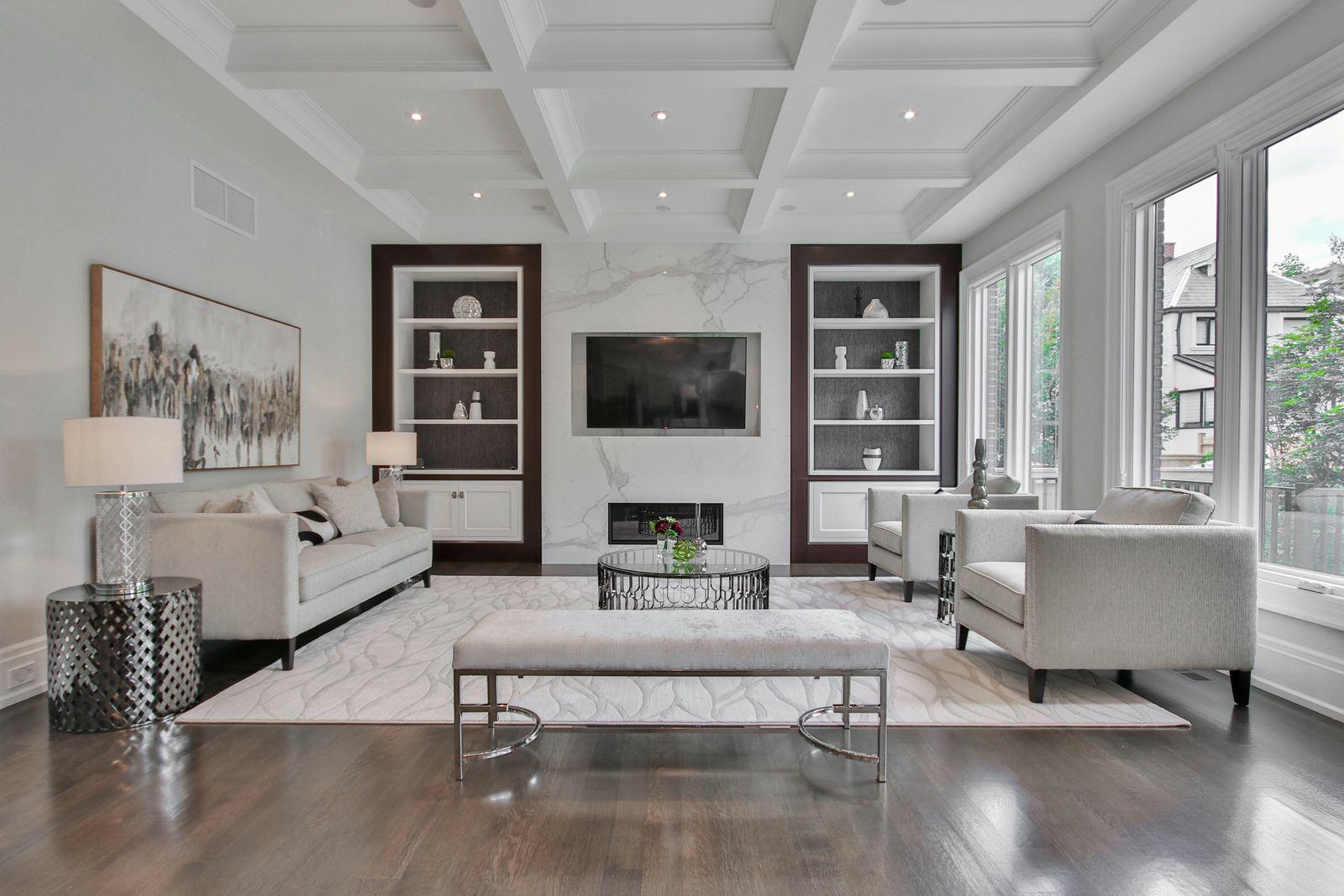 Bright living room with a coffered ceiling, built-in shelving and a wall-mounted TV