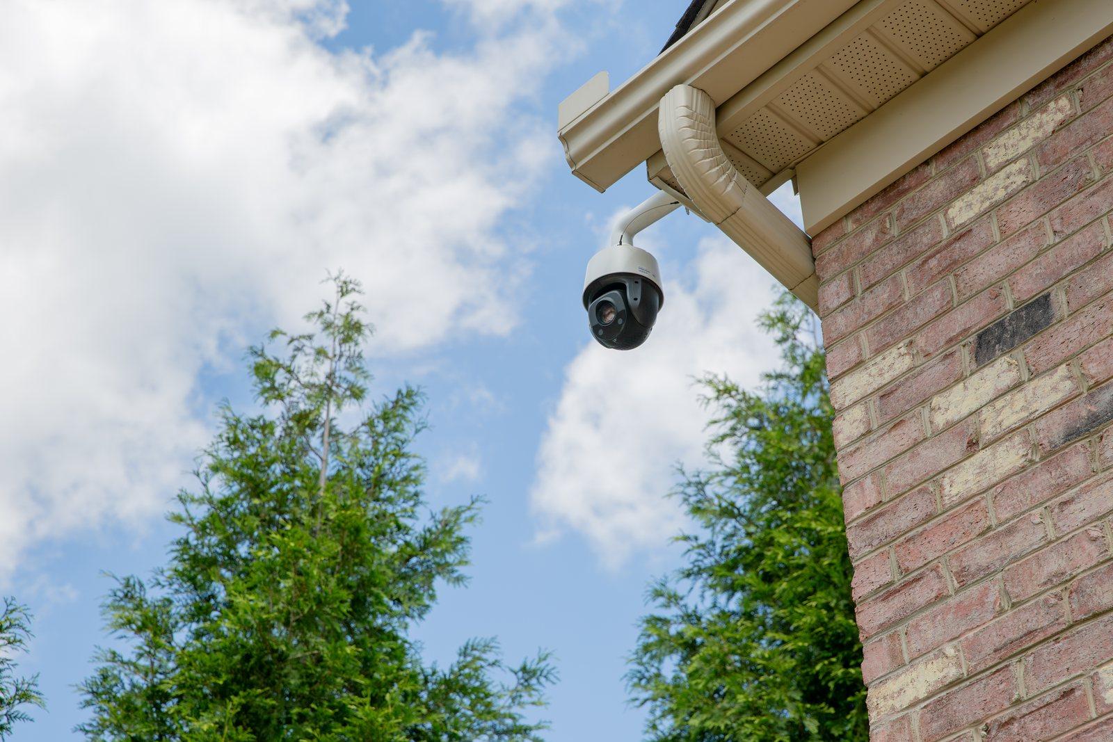 Dome security camera mounted under the eave of a brick home